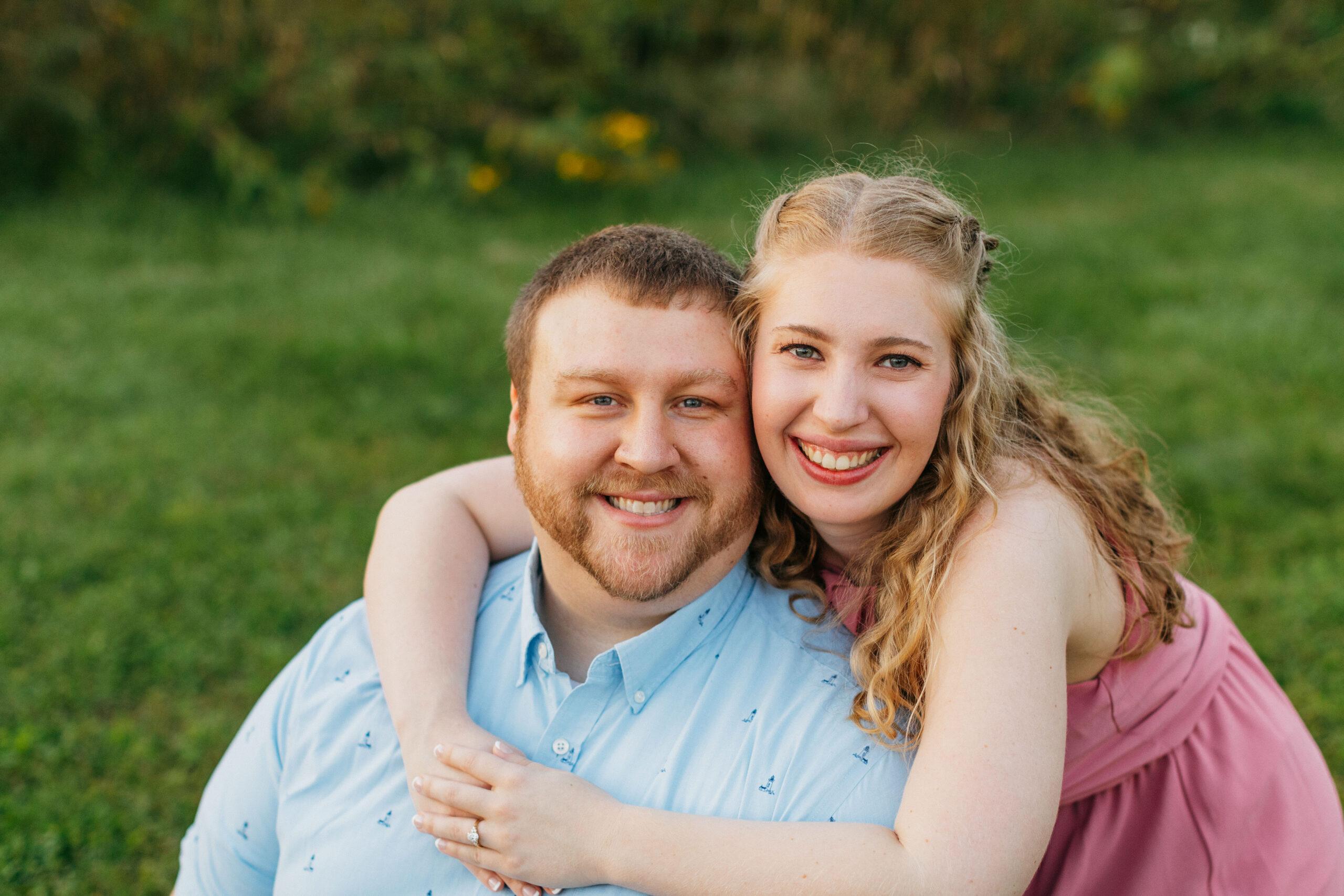 A photo of Kyle and Emily sat down on some grass and smiling.